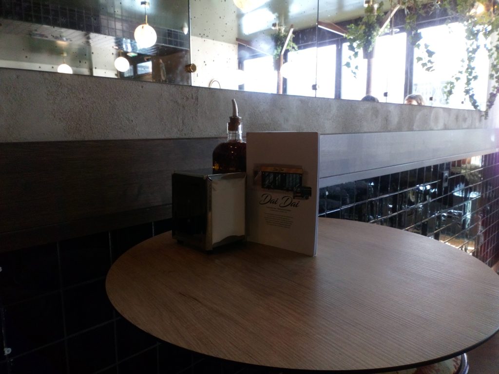 Photo d'une table ronde avec de l'huile à pizza, un distributeur de serviettes et le menu
