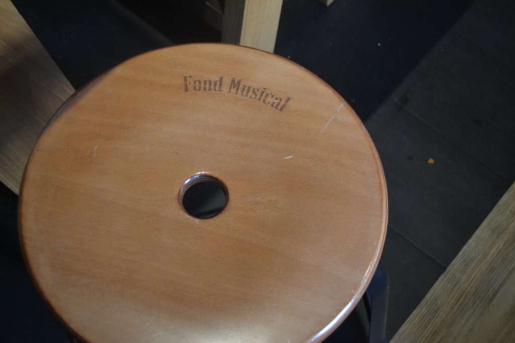 Photo d'un tabouret en bois sur lequel est gravé "Fond Musical"