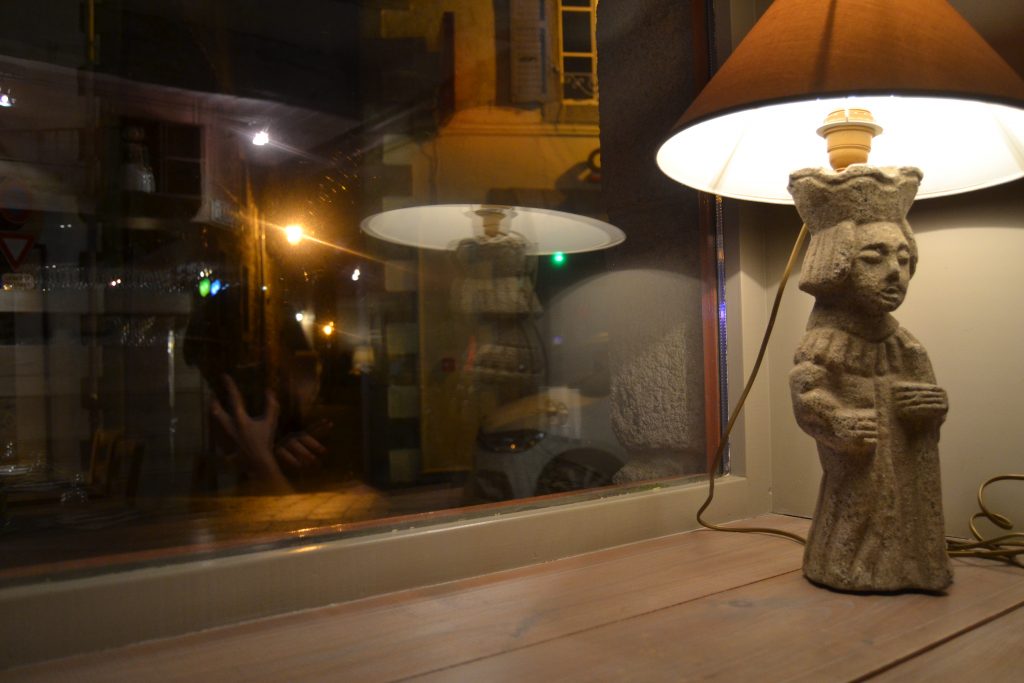 Photo d'un rebord de fenêtre avec une lampe dont le pied est une statuette de granit
